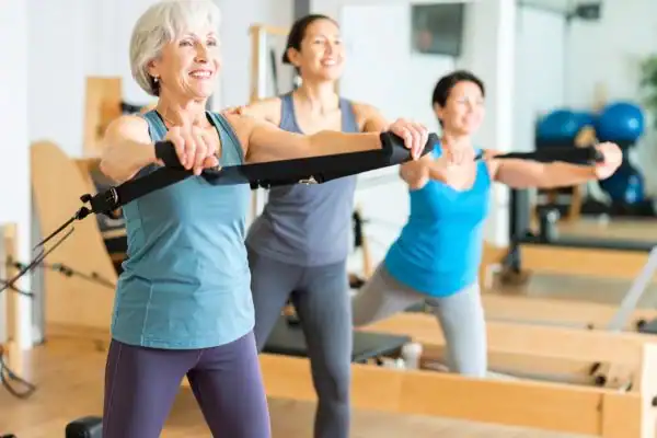 Toning Arms After 60: Empowering Womens Fitness Through Effective Weight Training 2 older woman doing weight training Romford and resistance in the gym to tone upper arms
